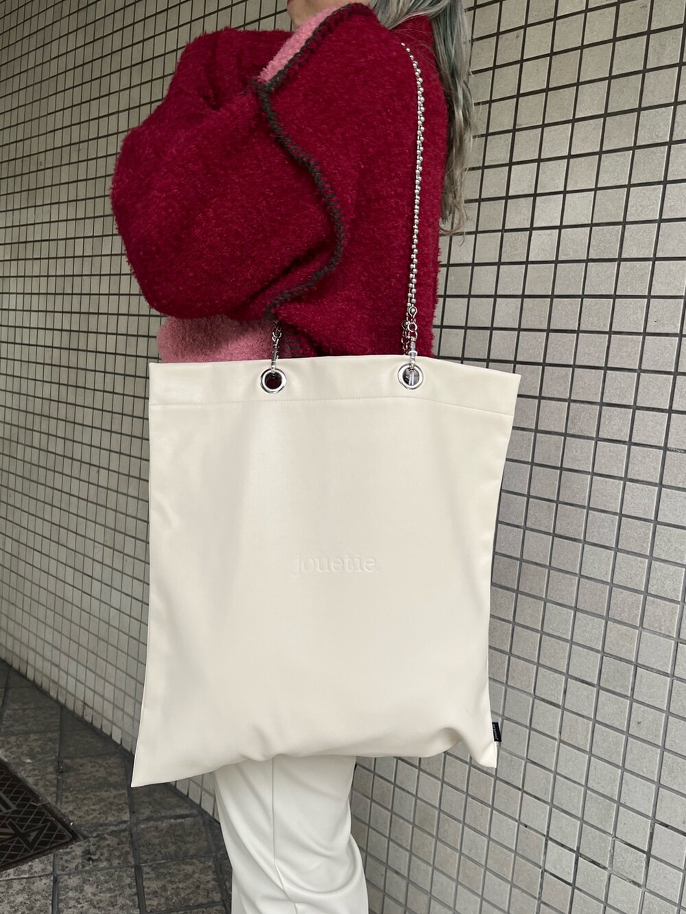 ホワイト系のハンドバッグ、レッド系のニット/セーター、ホワイト系のその他パンツを着用したレディースの冬コーディネートの7枚目の写真