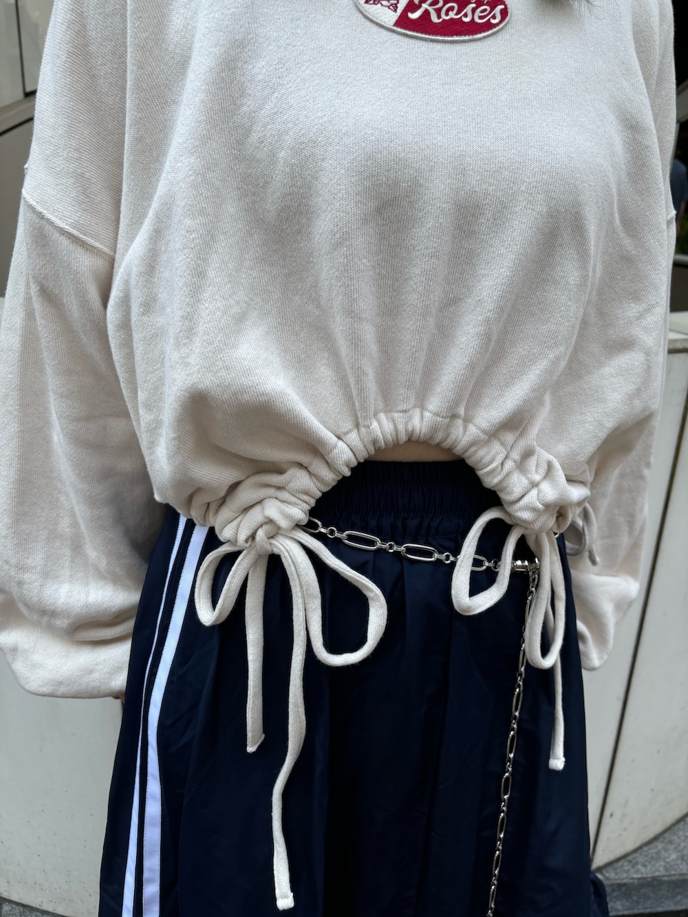 ブルー系のスカート、ホワイト系のスウェット、シルバー系のベルトを着用したレディースの夏コーディネートの6枚目の写真