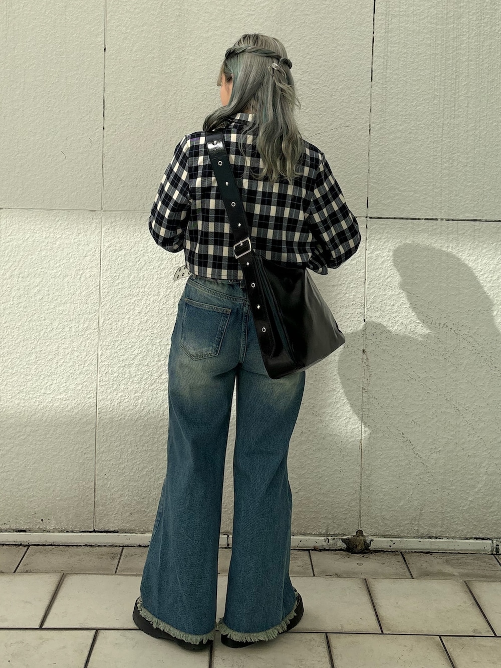 ブルー系のデニムパンツ、ブラック系のショルダーバッグ、ホワイト系のTシャツ/カットソーを着用したレディースの冬コーディネートの3枚目の写真