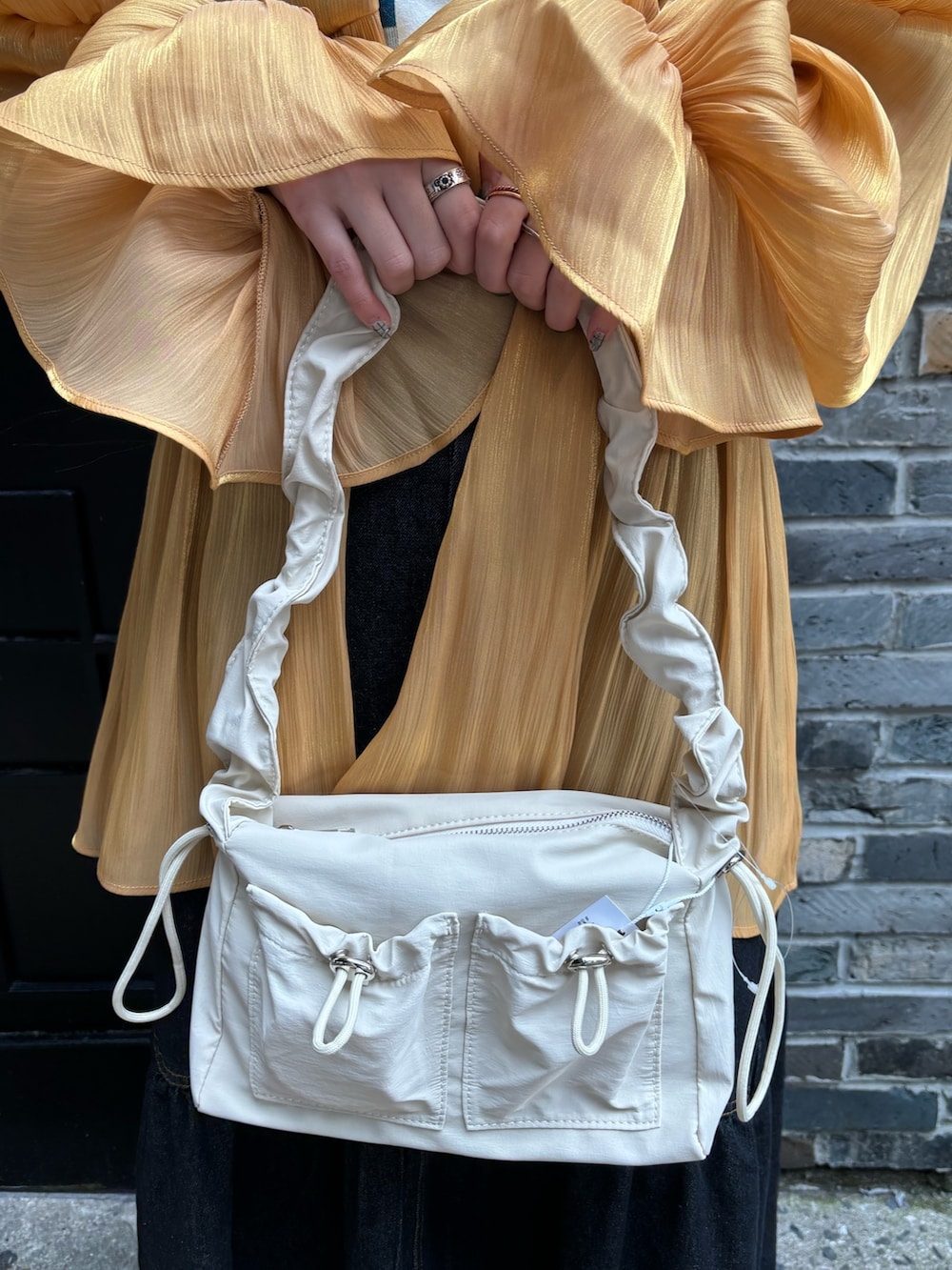 オレンジ系のシャツ/ブラウス、ホワイト系のTシャツ/カットソー、ホワイト系のショルダーバッグを着用したレディースの春コーディネートの10枚目の写真