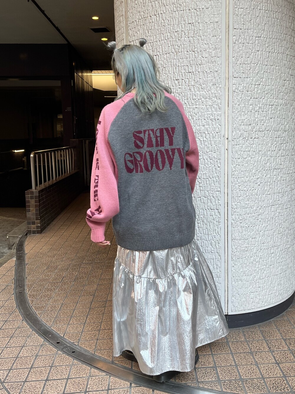 グレー系のニット/セーター、ブラック系のボストンバッグ、シルバー系のスカートを着用したレディースの冬コーディネートの4枚目の写真