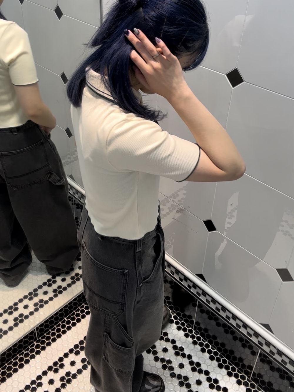 ブラック系のデニムパンツ、ホワイト系のポロシャツを着用したレディースの夏コーディネートの2枚目の写真