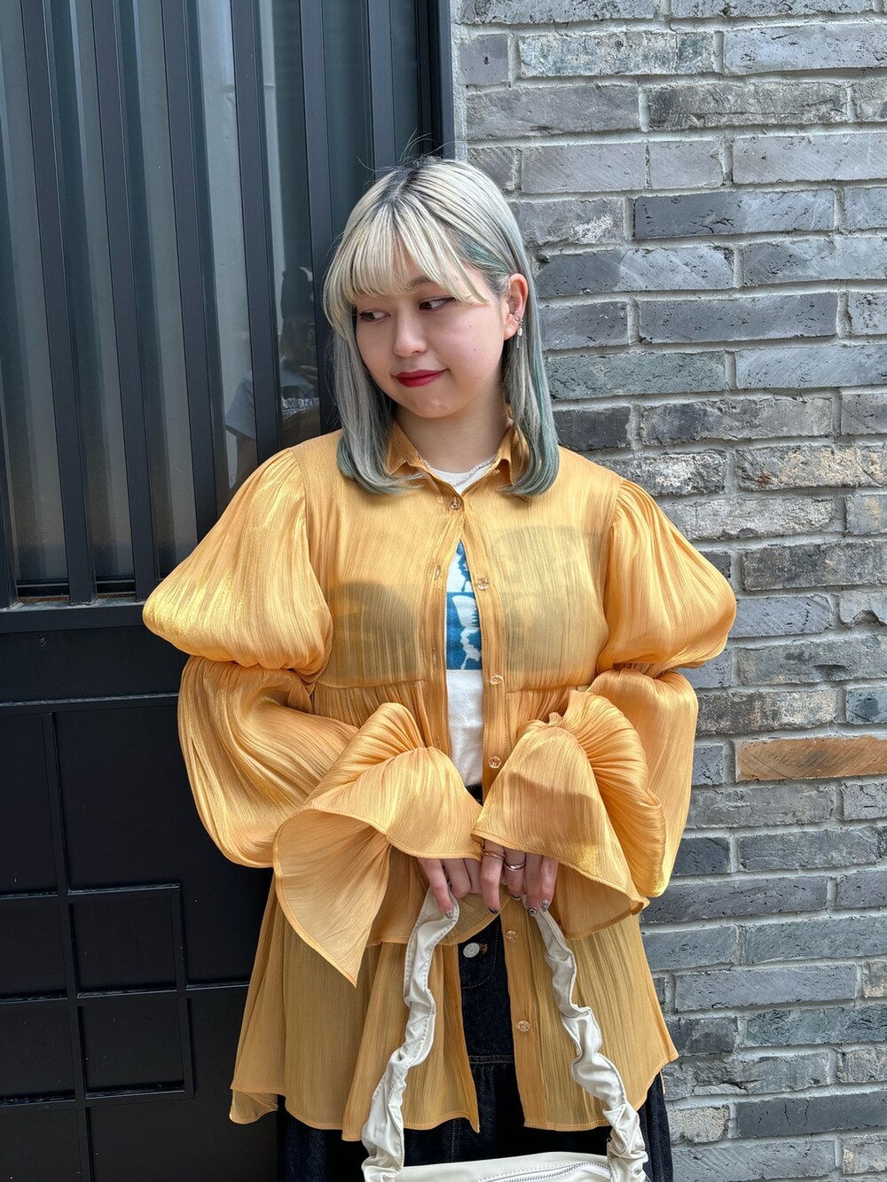 オレンジ系のシャツ/ブラウス、ホワイト系のTシャツ/カットソー、ホワイト系のショルダーバッグを着用したレディースの春コーディネートの6枚目の写真