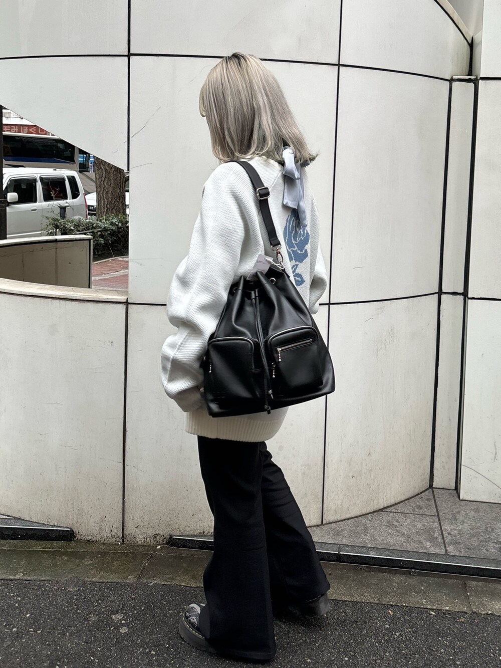 ホワイト系のニット/セーター、ブルー系のシャツ/ブラウス、ブラック系のバックパック/リュックを着用したレディースの春コーディネートの3枚目の写真