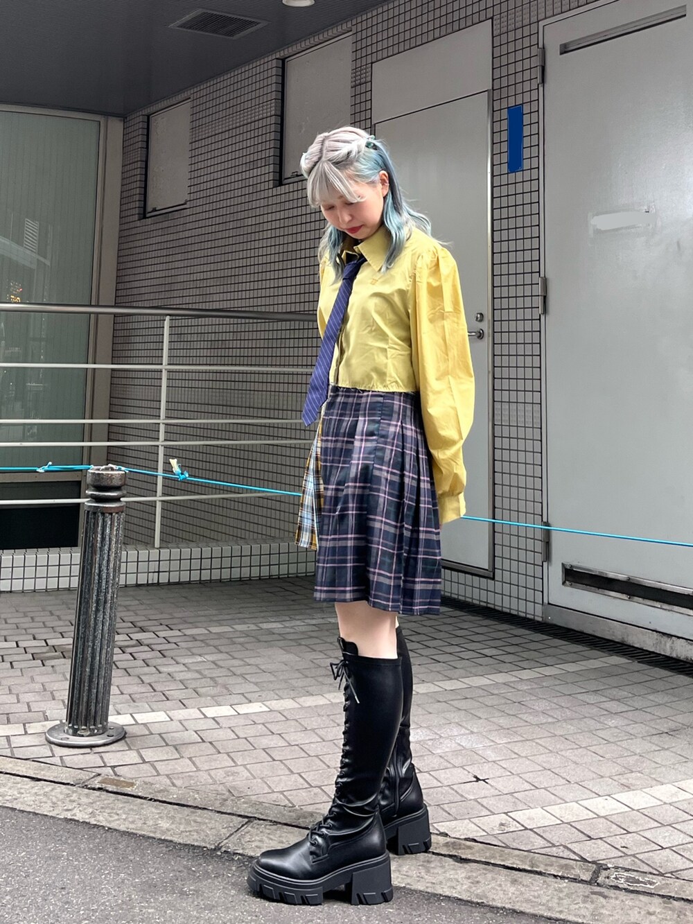 ブルー系のスカート、イエロー系のシャツ/ブラウス、ブラック系のブーツを着用したレディースの冬コーディネートの3枚目の写真