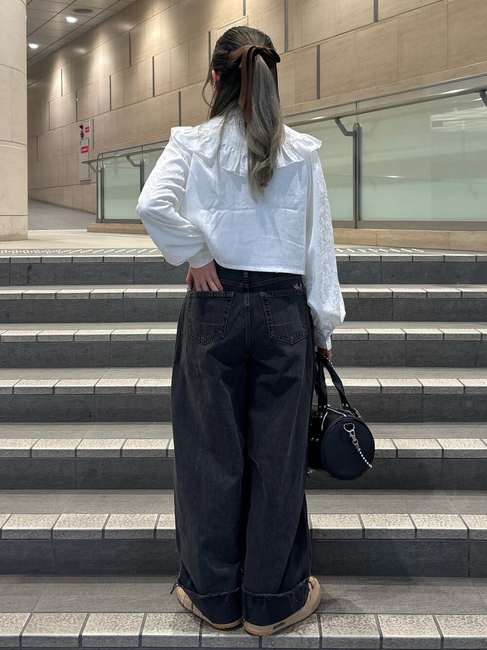 ブラック系のデニムパンツ、ブラック系のボストンバッグ、ホワイト系のシャツ/ブラウスを着用したレディースの春コーディネートの3枚目の写真