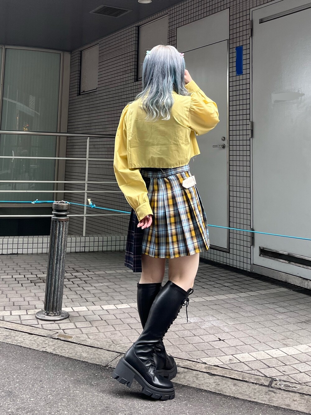 ブルー系のスカート、イエロー系のシャツ/ブラウス、ブラック系のブーツを着用したレディースの冬コーディネートの4枚目の写真