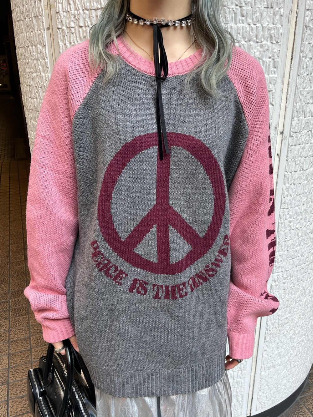 グレー系のニット/セーター、ブラック系のボストンバッグ、シルバー系のスカートを着用したレディースの冬コーディネートの6枚目の写真