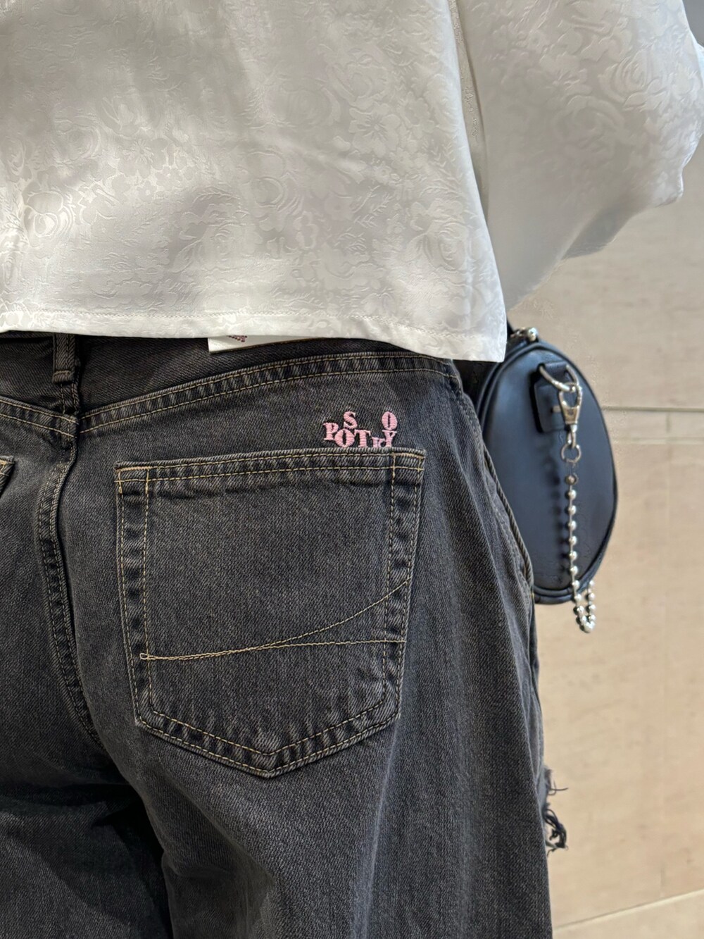 ブラック系のデニムパンツ、ブラック系のボストンバッグ、ホワイト系のシャツ/ブラウスを着用したレディースの春コーディネートの9枚目の写真