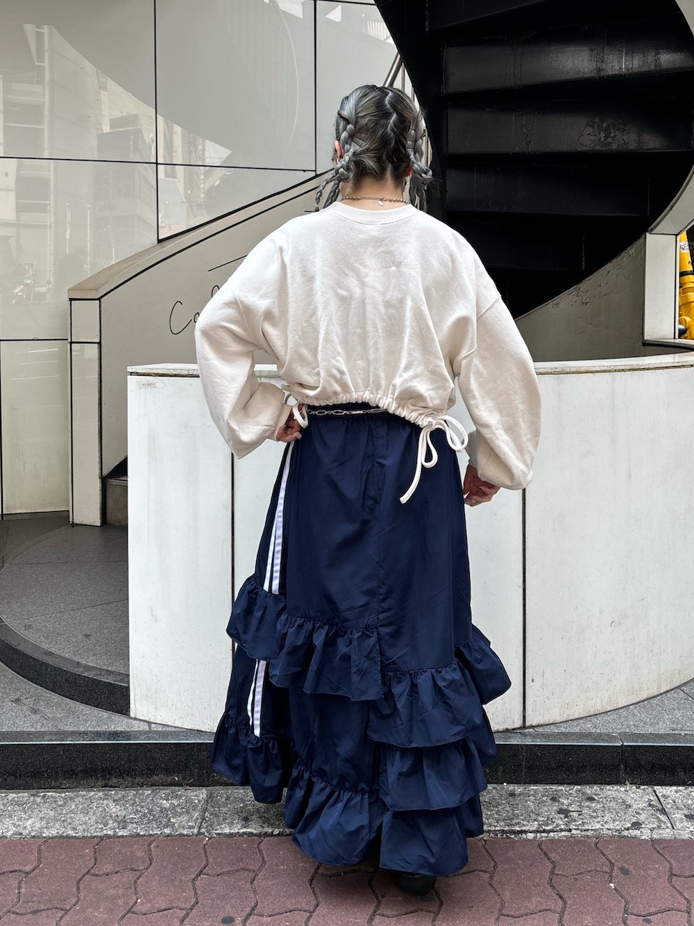 ブルー系のスカート、ホワイト系のスウェット、シルバー系のベルトを着用したレディースの夏コーディネートの3枚目の写真