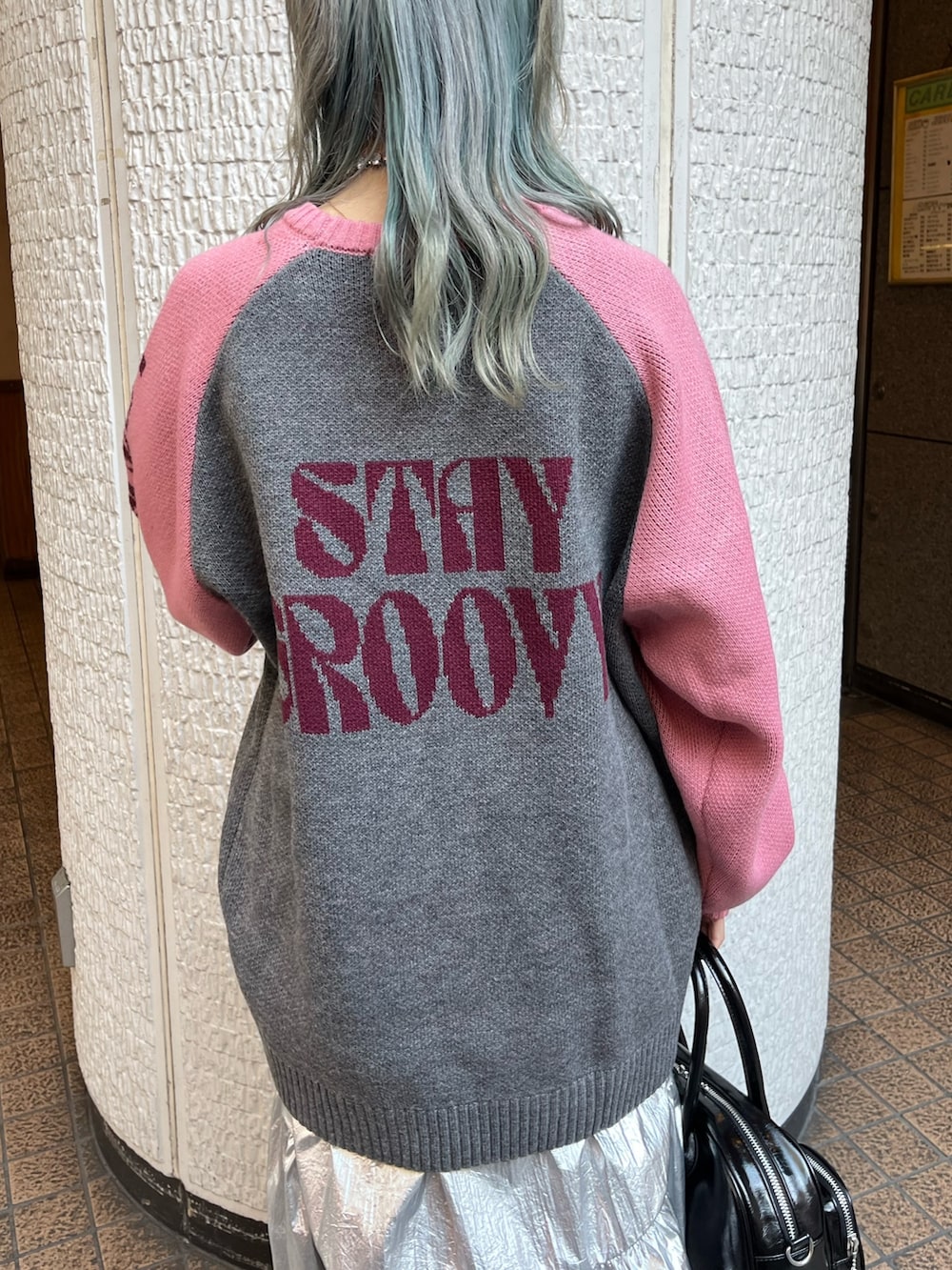 グレー系のニット/セーター、ブラック系のボストンバッグ、シルバー系のスカートを着用したレディースの冬コーディネートの9枚目の写真