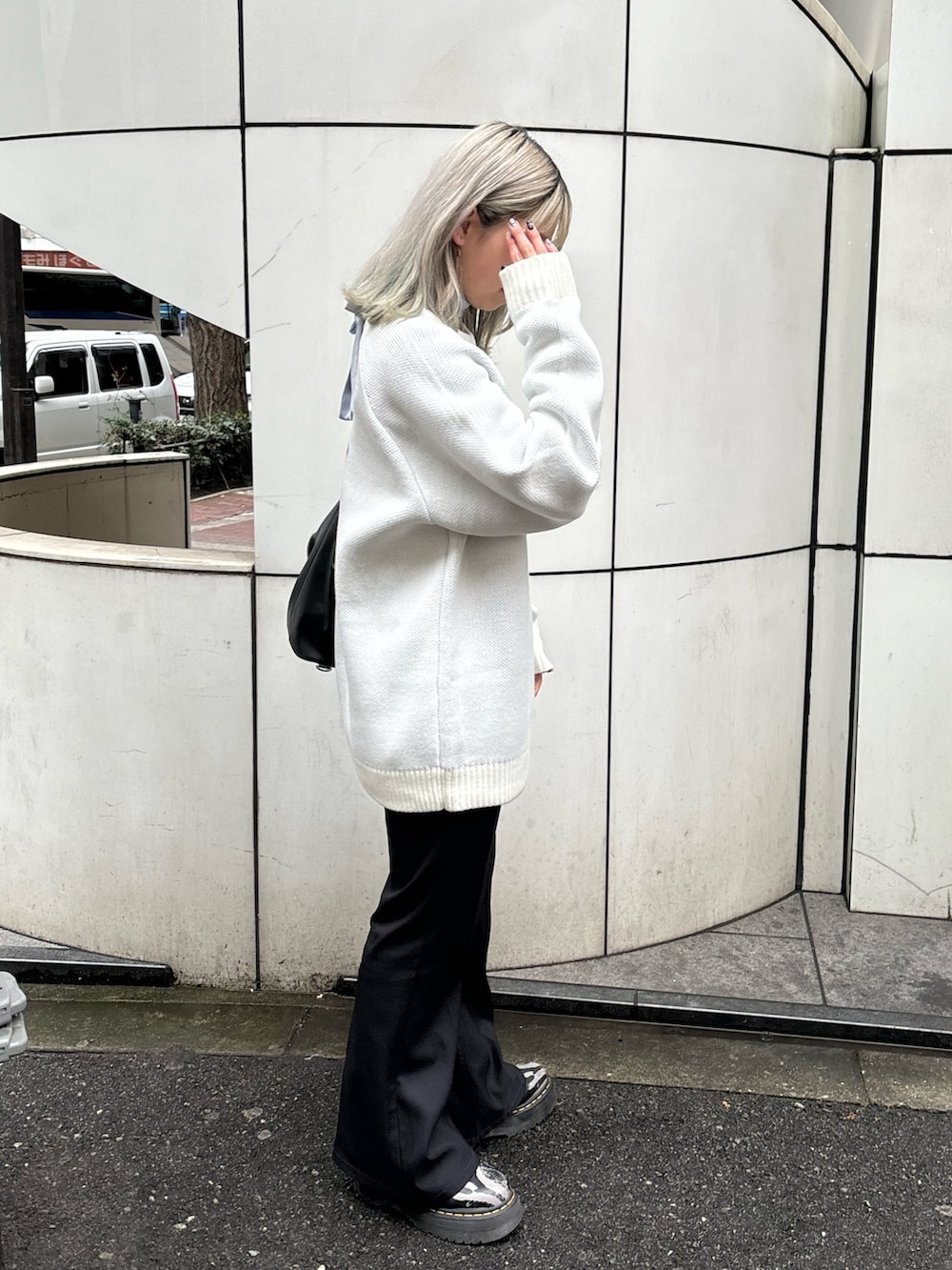 ホワイト系のニット/セーター、ブルー系のシャツ/ブラウス、ブラック系のバックパック/リュックを着用したレディースの春コーディネートの2枚目の写真