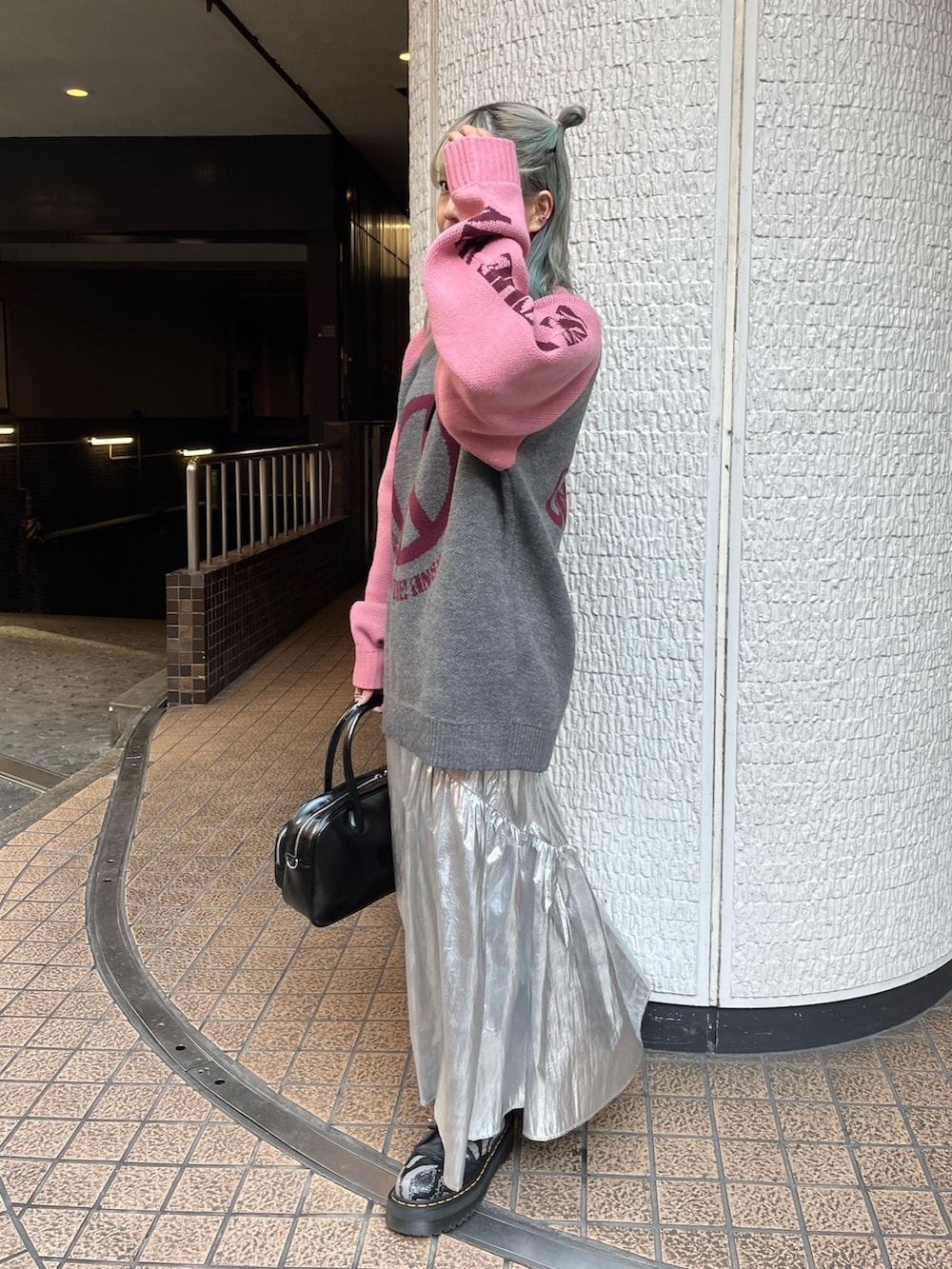 グレー系のニット/セーター、ブラック系のボストンバッグ、シルバー系のスカートを着用したレディースの冬コーディネートの3枚目の写真