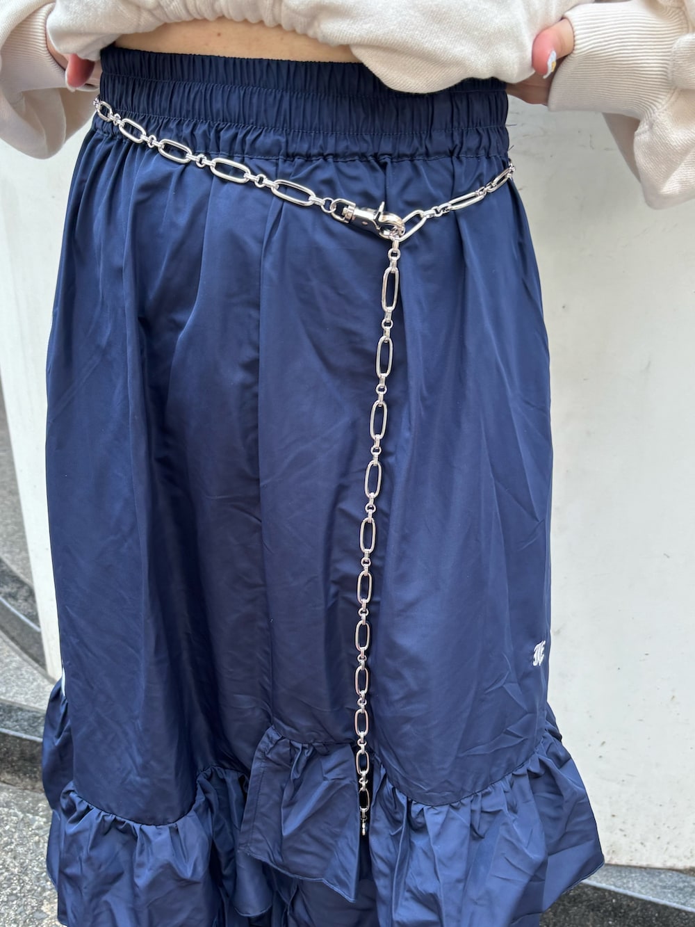 ブルー系のスカート、ホワイト系のスウェット、シルバー系のベルトを着用したレディースの夏コーディネートの9枚目の写真