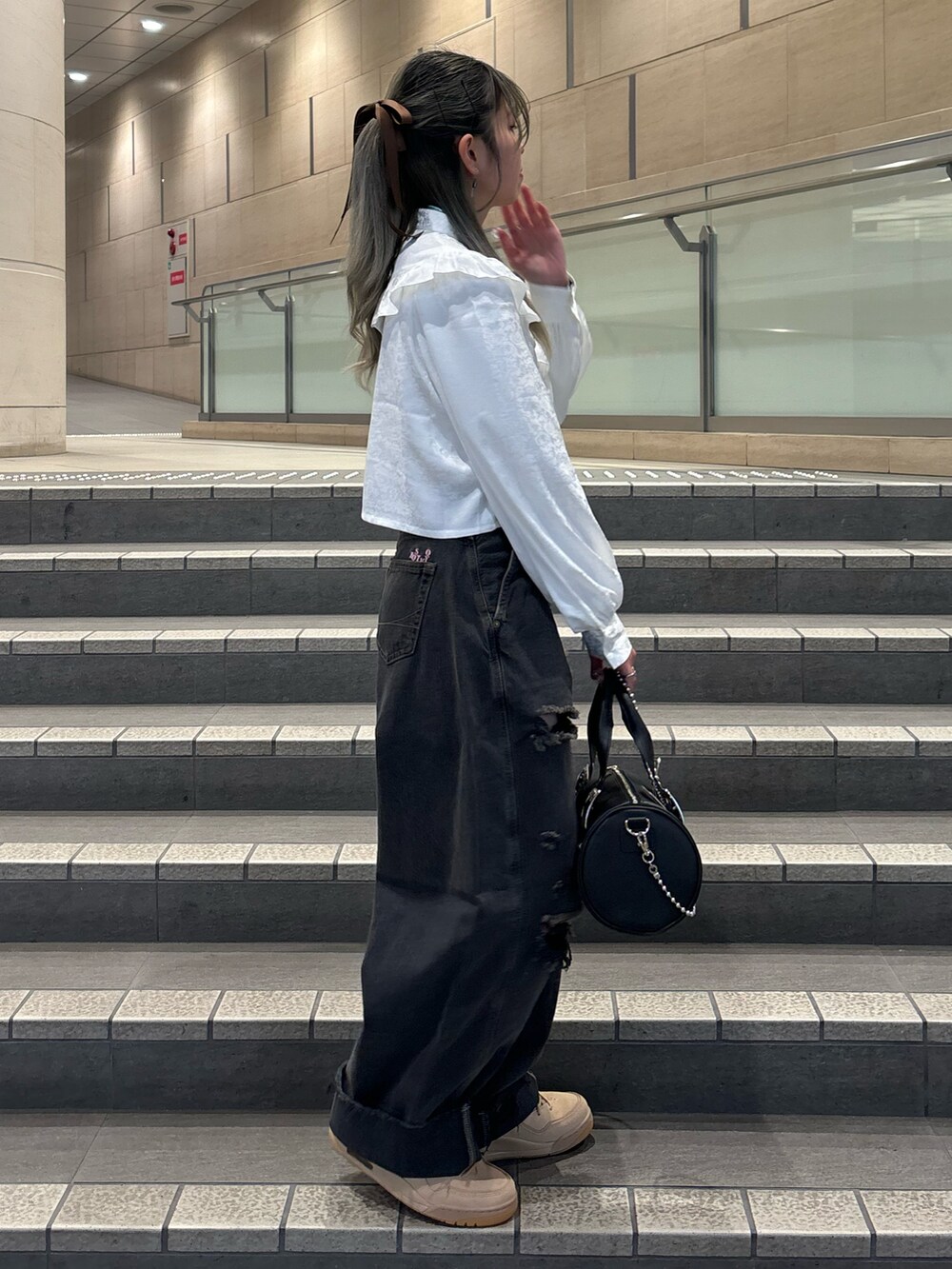 ブラック系のデニムパンツ、ブラック系のボストンバッグ、ホワイト系のシャツ/ブラウスを着用したレディースの春コーディネートの2枚目の写真