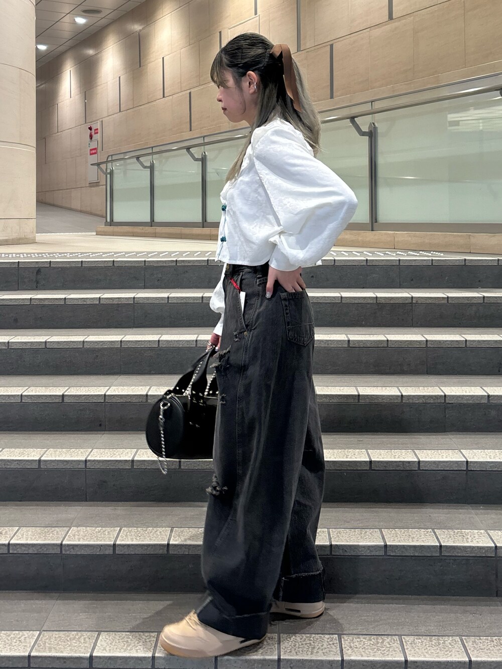 ブラック系のデニムパンツ、ブラック系のボストンバッグ、ホワイト系のシャツ/ブラウスを着用したレディースの春コーディネートの4枚目の写真