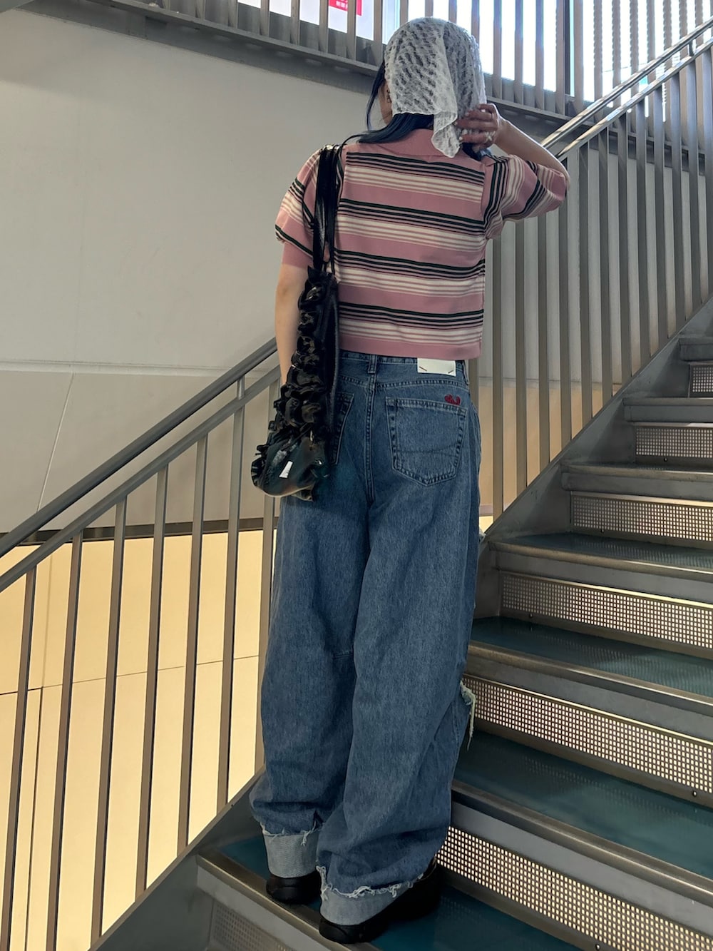 ブラック系のトートバッグ、ブルー系のデニムパンツ、ブルー系のデニムパンツを着用したレディースの春コーディネートの3枚目の写真