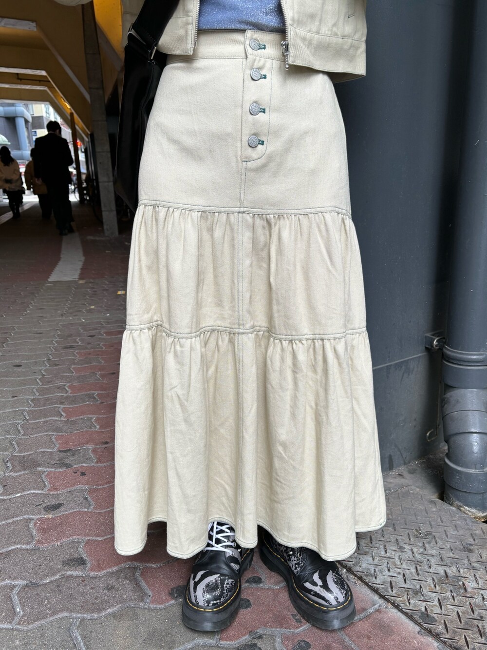 ブラック系のショルダーバッグ、ブルー系のTシャツ/カットソー、ホワイト系のワンピースを着用したレディースの春コーディネートの7枚目の写真