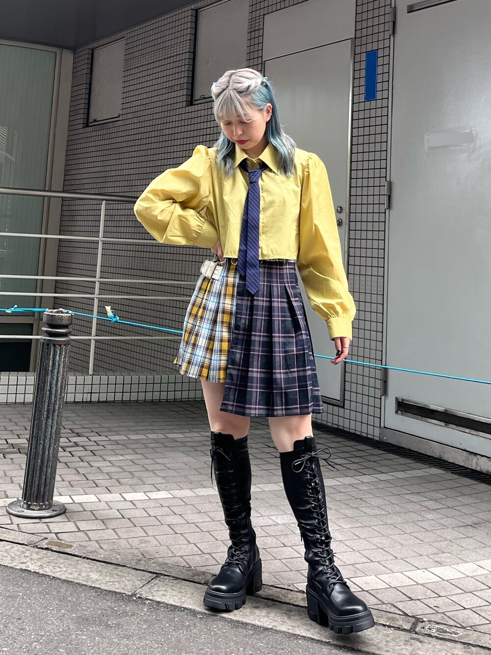 ブルー系のスカート、イエロー系のシャツ/ブラウス、ブラック系のブーツを着用したレディースの冬コーディネートの2枚目の写真