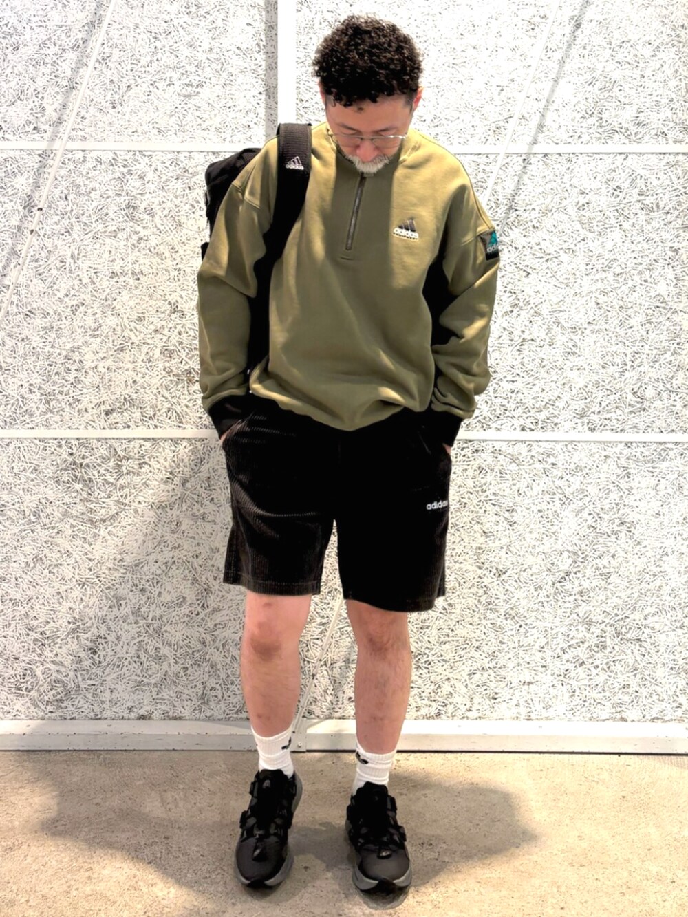 グリーン系のトップス、ブラック系のバックパック/リュック、ブラック系のパンツを着用したメンズの秋コーディネートの2枚目の写真