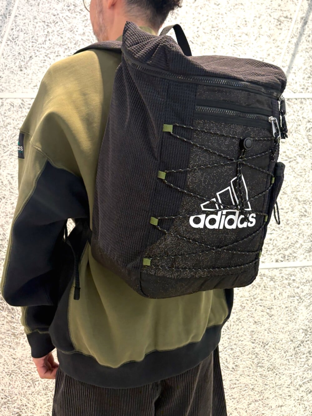 グリーン系のトップス、ブラック系のバックパック/リュック、ブラック系のパンツを着用したメンズの秋コーディネートの4枚目の写真