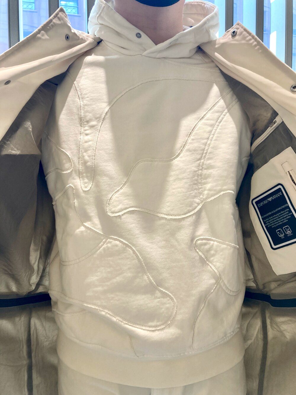 ベージュ系のスウェット、ベージュ系のステンカラーコート、ベージュ系のチノパンツを着用したメンズの春コーディネートの3枚目の写真