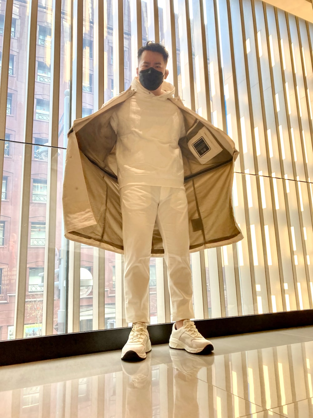 ベージュ系のスウェット、ベージュ系のステンカラーコート、ベージュ系のチノパンツを着用したメンズの春コーディネートの2枚目の写真