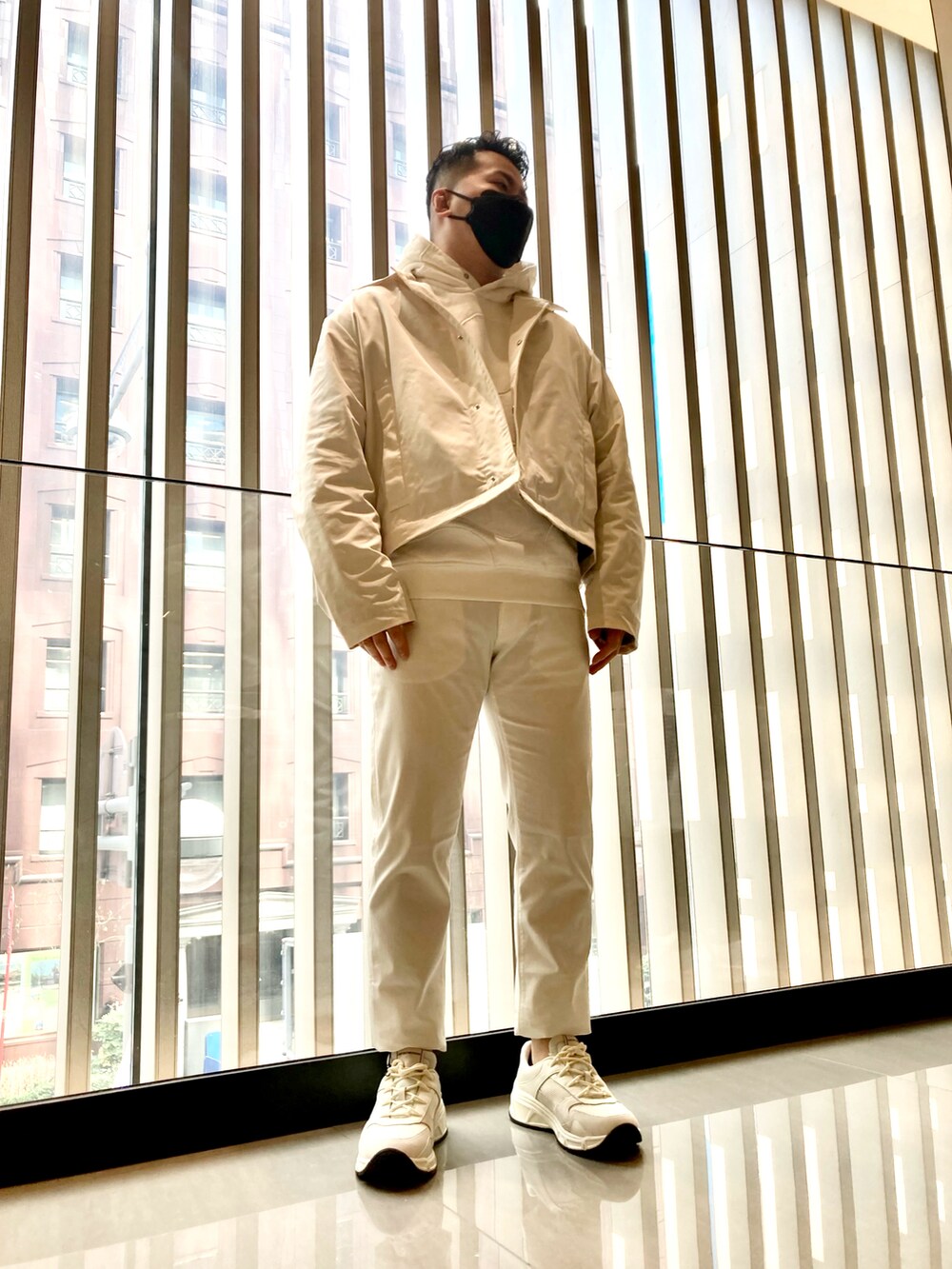 ベージュ系のスウェット、ベージュ系のステンカラーコート、ベージュ系のチノパンツを着用したメンズの春コーディネートの4枚目の写真