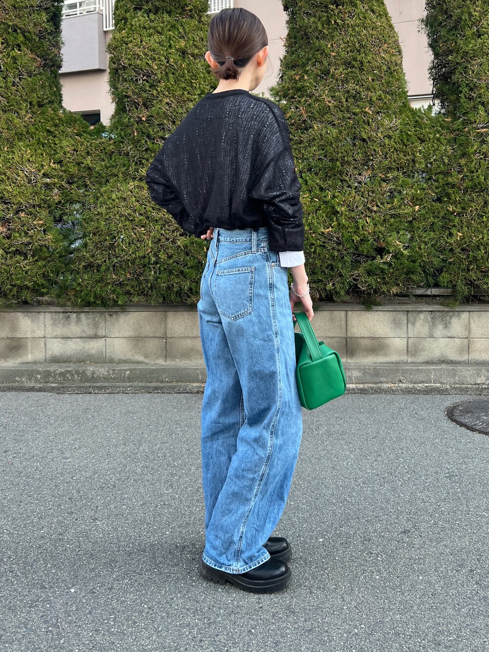 ブルー系のデニムパンツ、グリーン系のショルダーバッグ、ブラック系のニット/セーターを着用したレディースの夏コーディネートの3枚目の写真