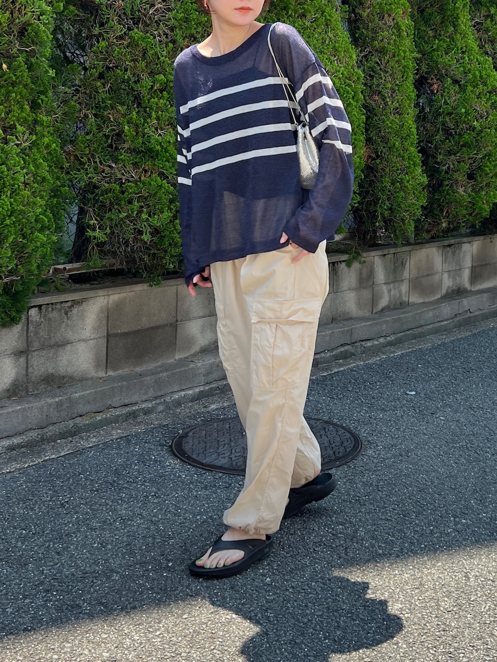 ホワイト系のパンツ、ブルー系のトップス、シルバー系のショルダーバッグを着用したレディースの夏コーディネートの2枚目の写真