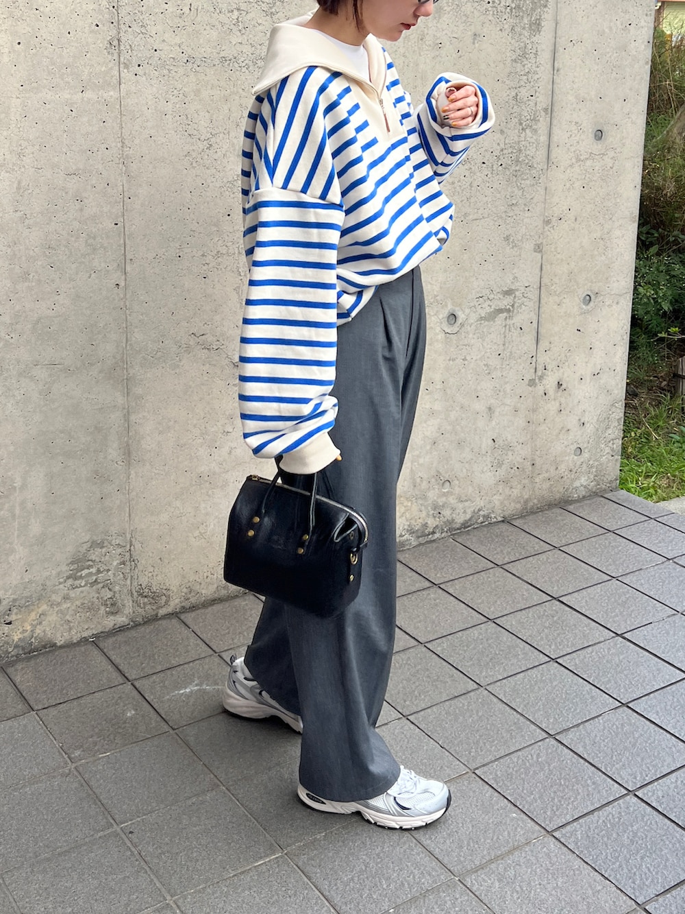 ブルー系のスウェット、グレー系のスラックス、ブラック系のボストンバッグを着用したレディースの冬コーディネートの2枚目の写真