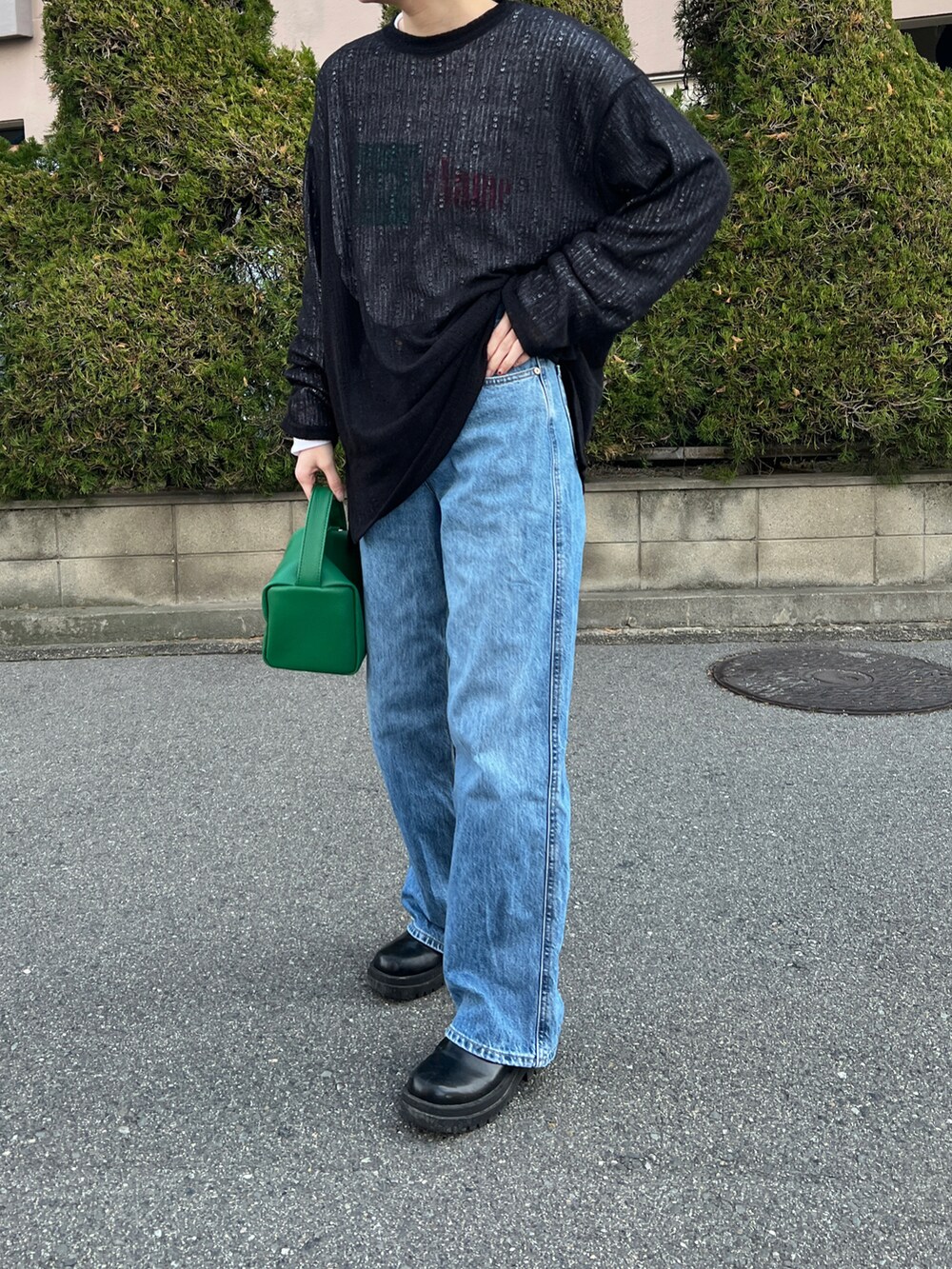 ブルー系のデニムパンツ、グリーン系のショルダーバッグ、ブラック系のニット/セーターを着用したレディースの夏コーディネートの2枚目の写真