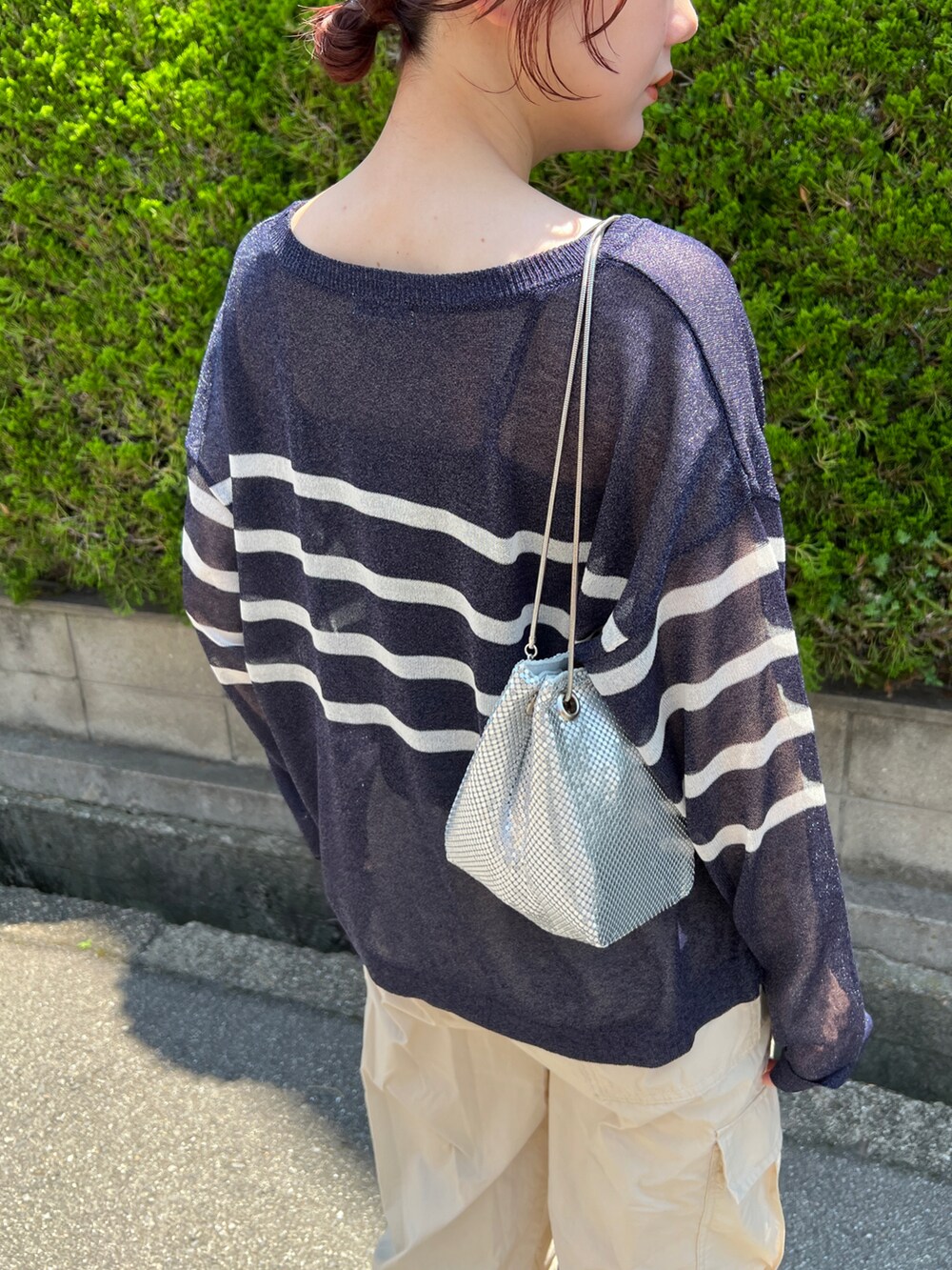 ホワイト系のパンツ、ブルー系のトップス、シルバー系のショルダーバッグを着用したレディースの夏コーディネートの4枚目の写真