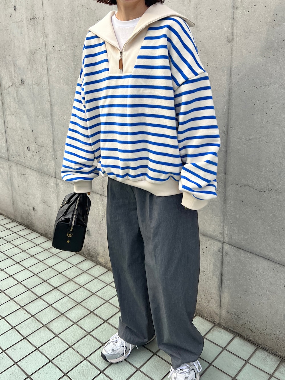 ブルー系のスウェット、グレー系のスラックス、ブラック系のボストンバッグを着用したレディースの冬コーディネートの4枚目の写真