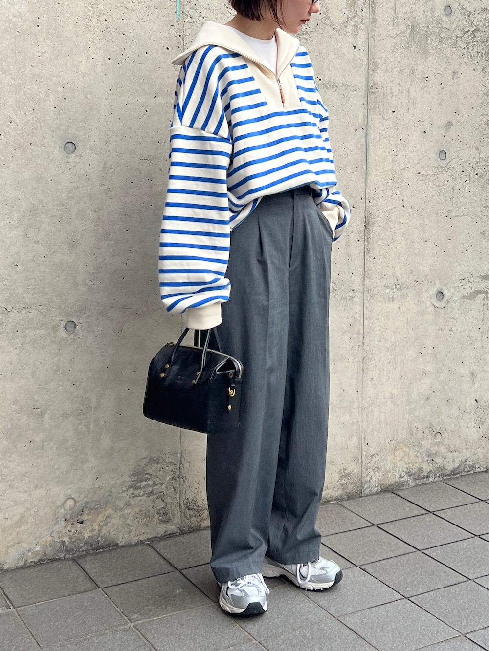 ブルー系のスウェット、グレー系のスラックス、ブラック系のボストンバッグを着用したレディースの冬コーディネートの3枚目の写真