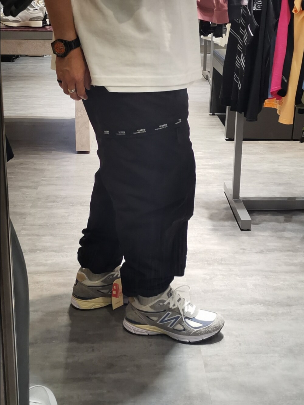 ホワイト系のTシャツ/カットソー、ブラック系のチノパンツ、グレー系のスニーカーを着用したメンズの春コーディネートの2枚目の写真