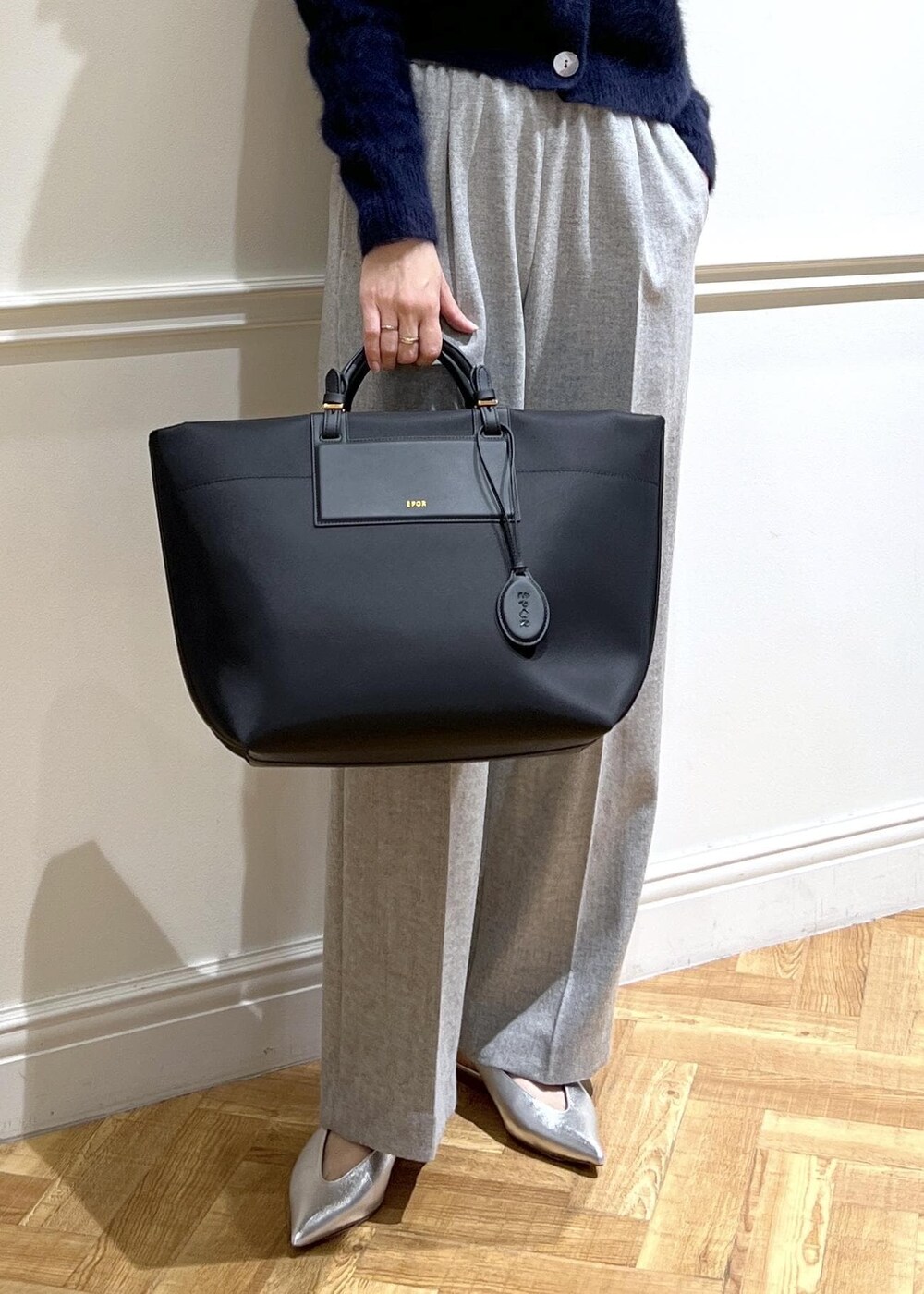 シルバー系のパンプス、ブラック系のトートバッグ、ブルー系のカーディガン/ボレロを着用したレディースの秋コーディネートの2枚目の写真