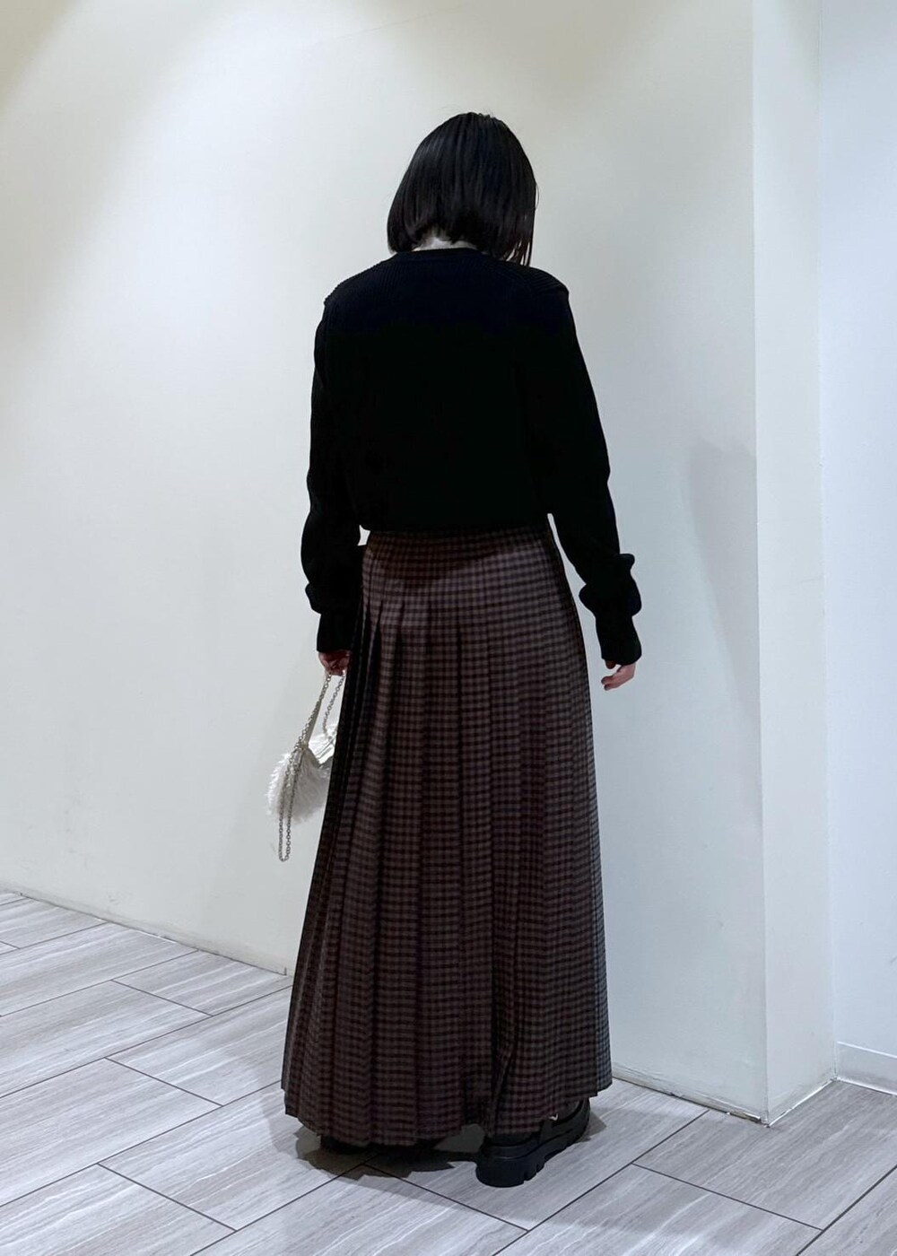 ブラック系のその他シューズ、グレー系のスカート、ホワイト系のニット/セーターを着用したレディースの秋コーディネートの4枚目の写真