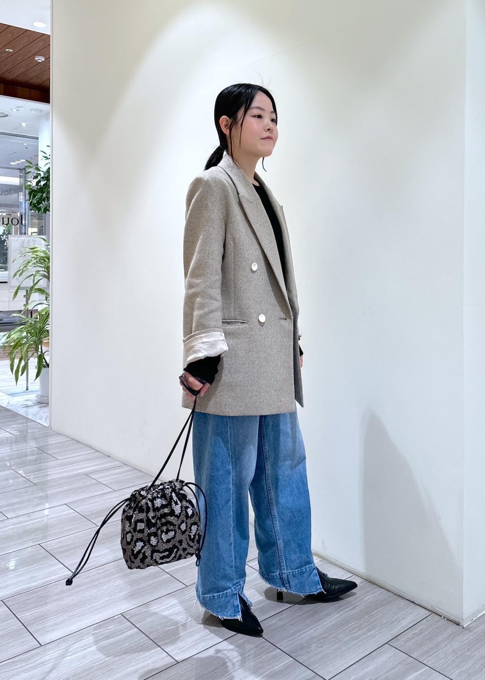 ブルー系のデニムパンツ、ブラック系のブーツ、グレー系のハンドバッグを着用したレディースの秋コーディネートの5枚目の写真