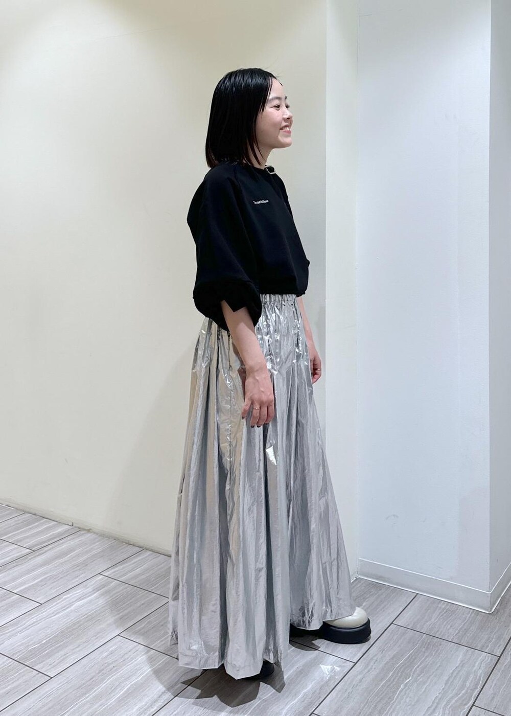 ベージュ系のサンダル、ベージュ系のトートバッグ、シルバー系のスカートを着用したレディースの秋コーディネートの5枚目の写真