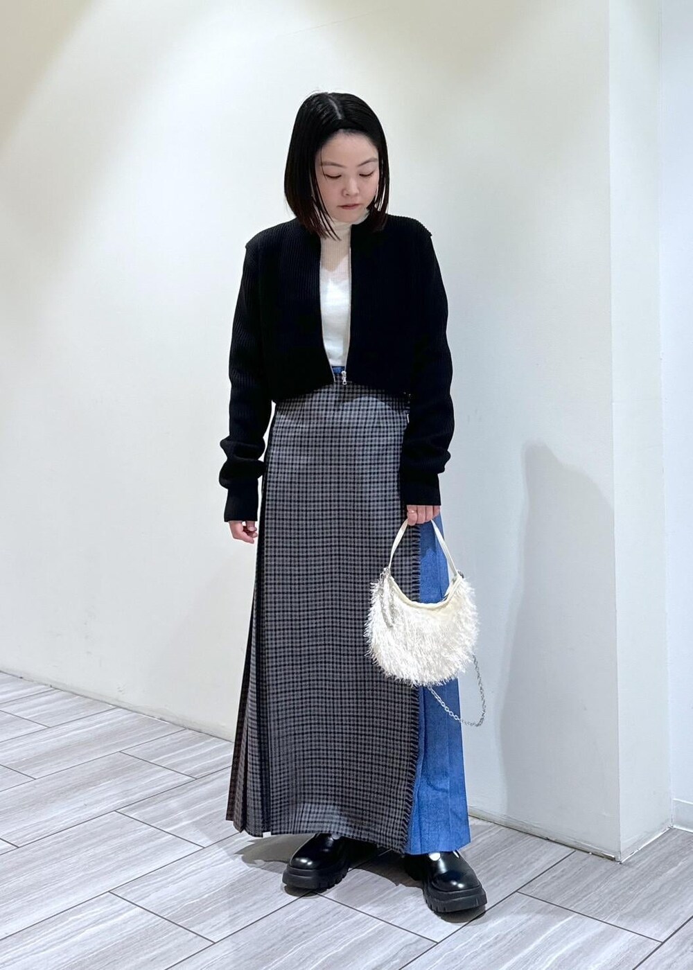 ブラック系のその他シューズ、グレー系のスカート、ホワイト系のニット/セーターを着用したレディースの秋コーディネートの6枚目の写真