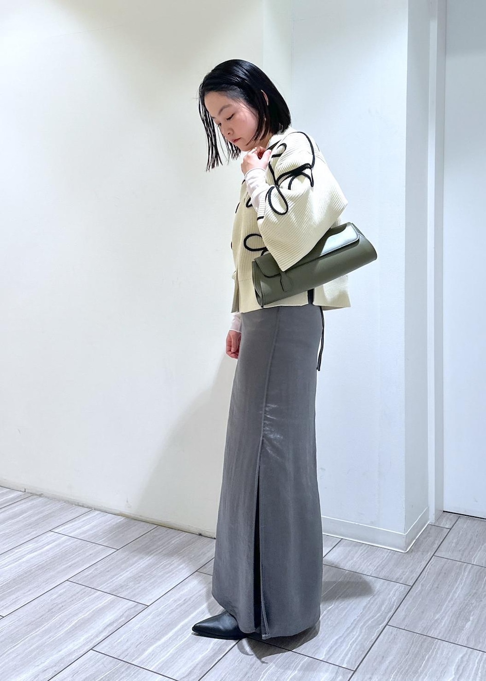 ホワイト系のカーディガン/ボレロ、ブラック系のブーツ、ホワイト系のTシャツ/カットソーを着用したレディースの秋コーディネートの2枚目の写真