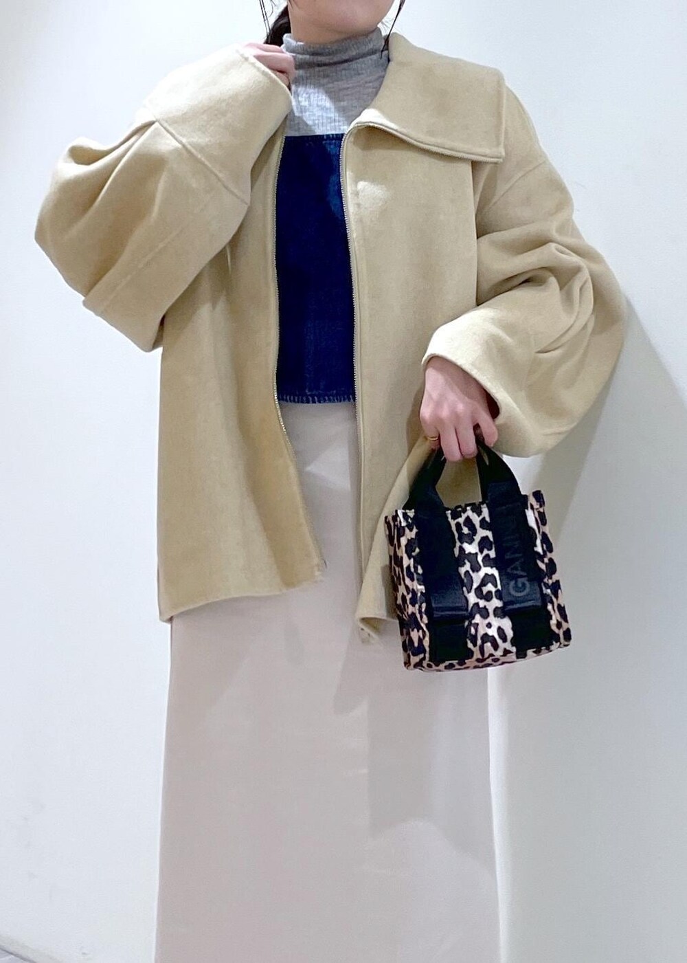 ベージュ系のトートバッグ、ブラック系のブーツ、ホワイト系のスカートを着用したレディースの秋コーディネートの6枚目の写真