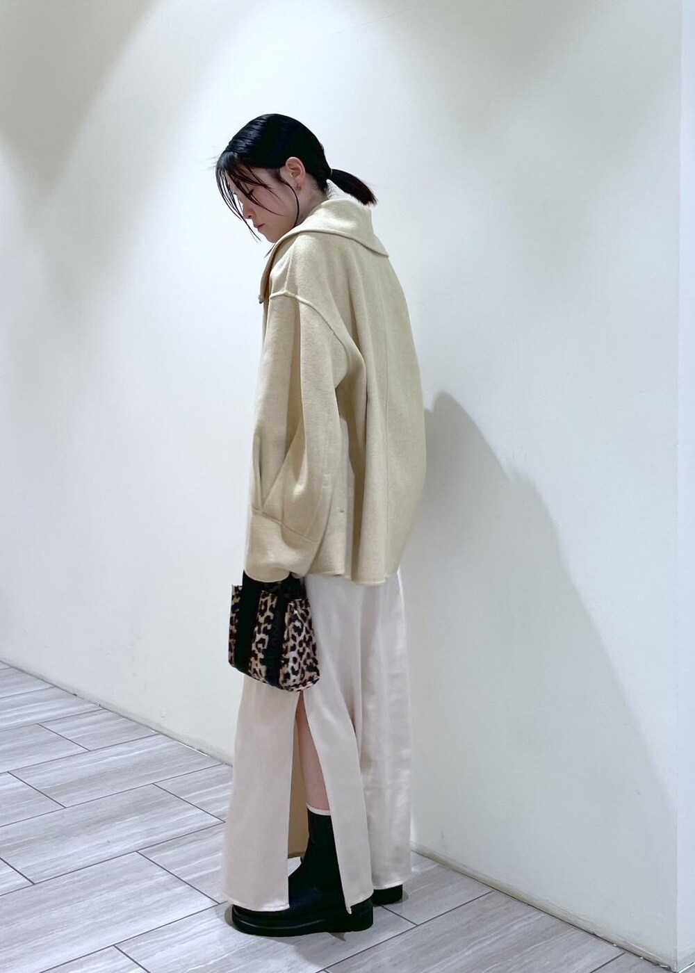 ベージュ系のトートバッグ、ブラック系のブーツ、ホワイト系のスカートを着用したレディースの秋コーディネートの3枚目の写真