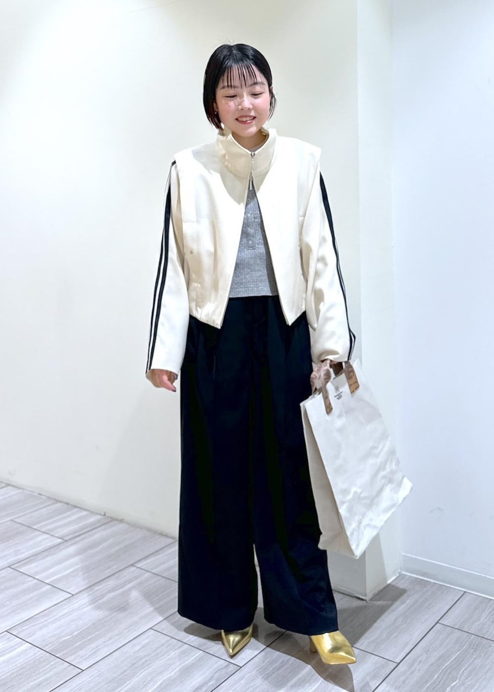 ゴールド系のその他シューズ、ホワイト系のブルゾン、グレー系のTシャツ/カットソーを着用したレディースの春コーディネートの2枚目の写真