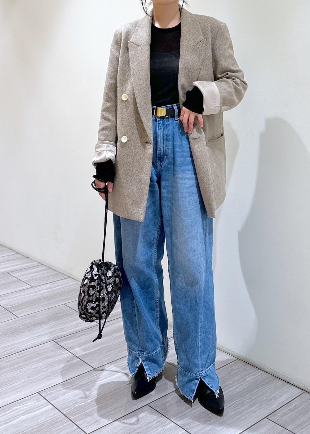 ブルー系のデニムパンツ、ブラック系のブーツ、グレー系のハンドバッグを着用したレディースの秋コーディネートの6枚目の写真