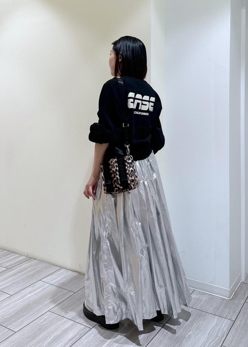 ベージュ系のサンダル、ベージュ系のトートバッグ、シルバー系のスカートを着用したレディースの秋コーディネートの3枚目の写真