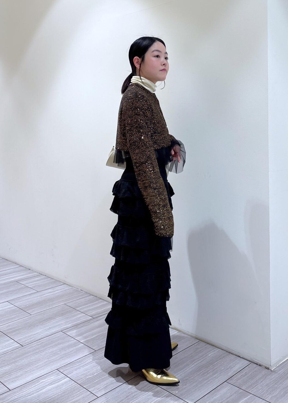 ゴールド系のブーツ、ホワイト系のショルダーバッグ、ブラック系のスカートを着用したレディースの秋コーディネートの4枚目の写真