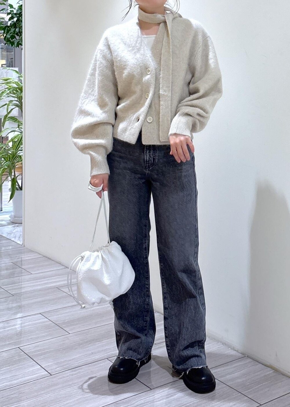 ホワイト系のカーディガン/ボレロ、ブラック系のブーツ、グレー系のデニムパンツを着用したレディースの秋コーディネートの6枚目の写真