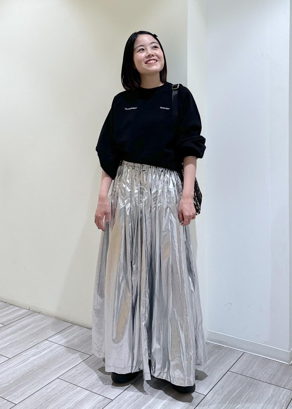 ベージュ系のサンダル、ベージュ系のトートバッグ、シルバー系のスカートを着用したレディースの秋コーディネートの6枚目の写真